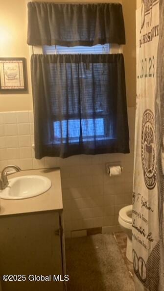 bathroom with tile walls, vanity, tile patterned floors, and toilet