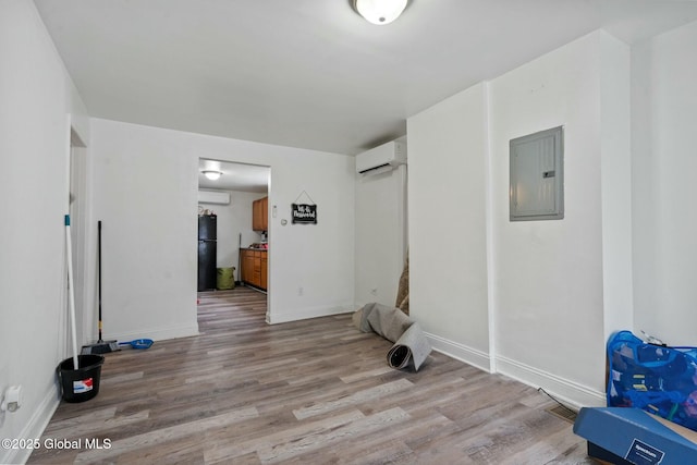 interior space with an AC wall unit, electric panel, and light wood-type flooring