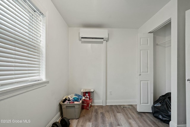 bedroom with a wall unit AC and light hardwood / wood-style flooring