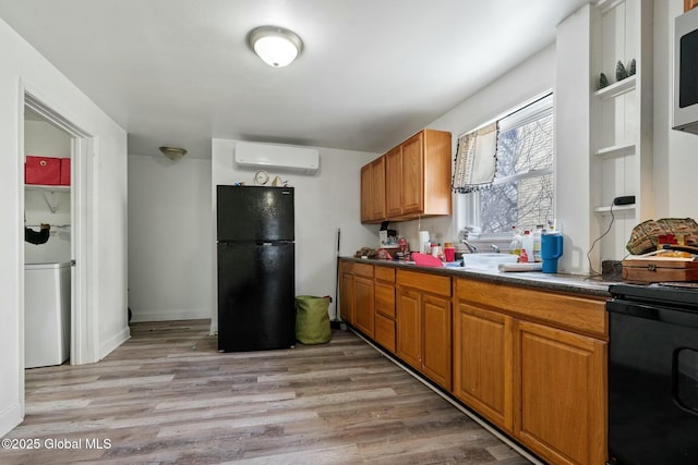 kitchen with a wall mounted air conditioner, light hardwood / wood-style flooring, and black appliances