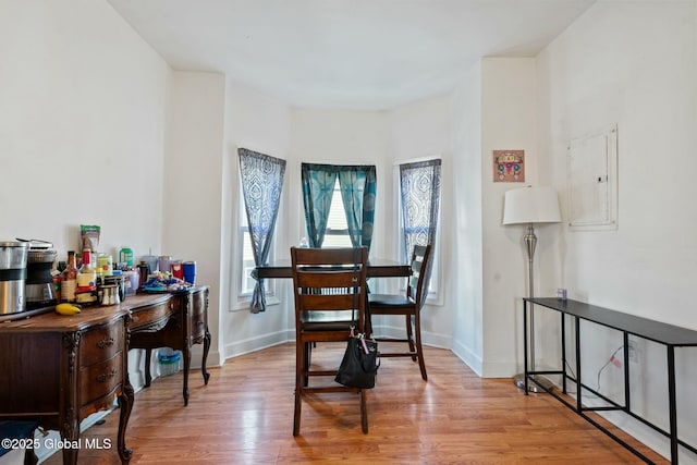 dining space featuring electric panel and light hardwood / wood-style flooring