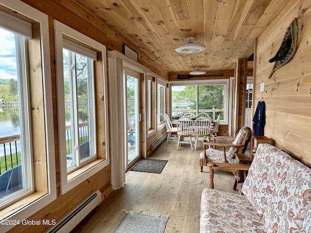 sunroom / solarium featuring baseboard heating, a water view, a healthy amount of sunlight, and wooden ceiling