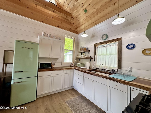 kitchen featuring refrigerator, decorative light fixtures, white cabinetry, butcher block counters, and sink