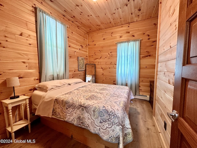 bedroom featuring wood ceiling, wood-type flooring, a baseboard heating unit, and wood walls