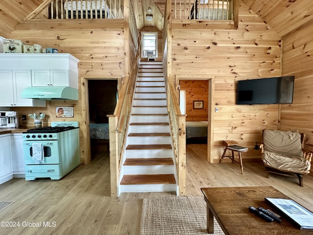 stairway featuring wooden walls, high vaulted ceiling, and hardwood / wood-style floors