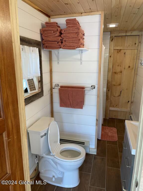 bathroom with a baseboard heating unit, wood ceiling, wooden walls, and toilet