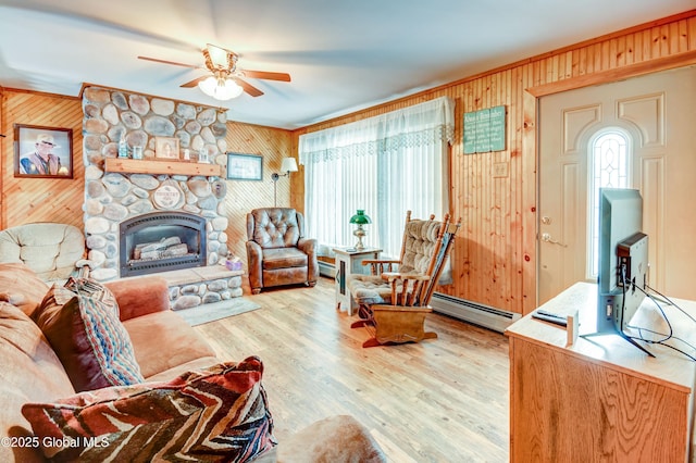 living room with hardwood / wood-style floors, a fireplace, a baseboard radiator, ornamental molding, and ceiling fan