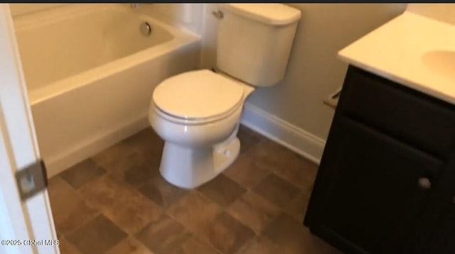 bathroom with a washtub, vanity, and toilet