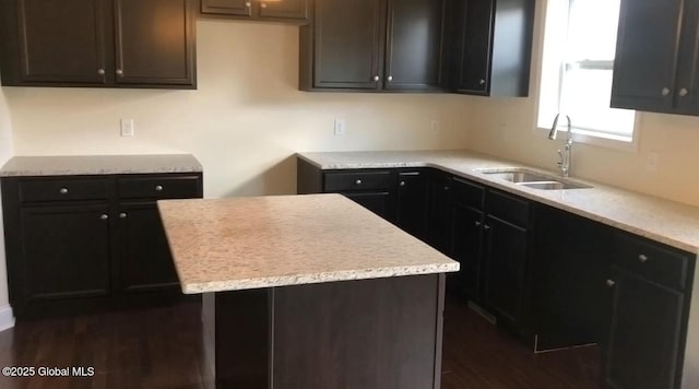 kitchen with light stone countertops, a center island, sink, and dark hardwood / wood-style floors