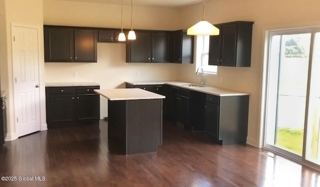 kitchen featuring a kitchen island, sink, dark hardwood / wood-style floors, and decorative light fixtures