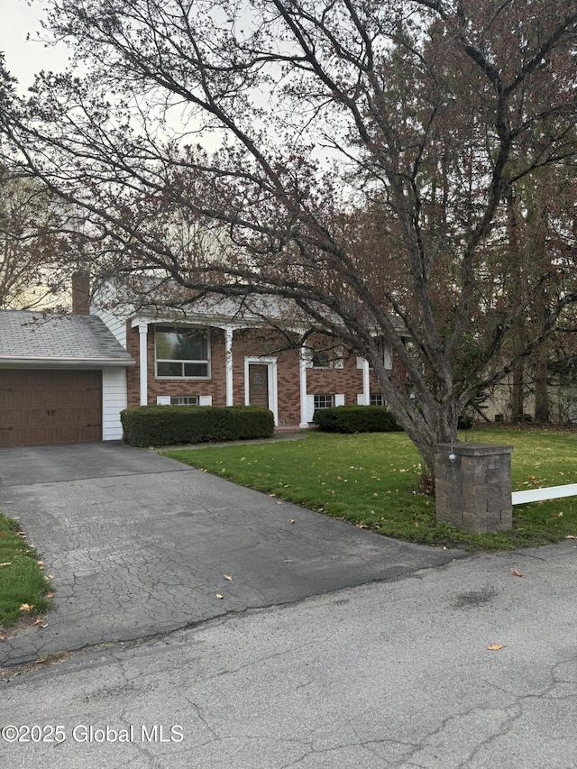 view of property hidden behind natural elements with a front yard, driveway, and an attached garage
