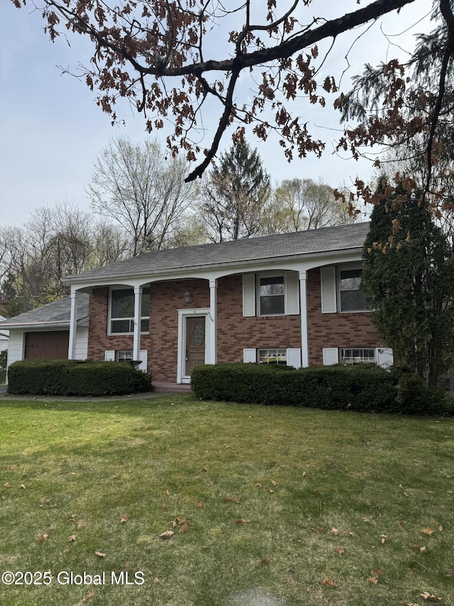 raised ranch featuring a garage, brick siding, and a front lawn
