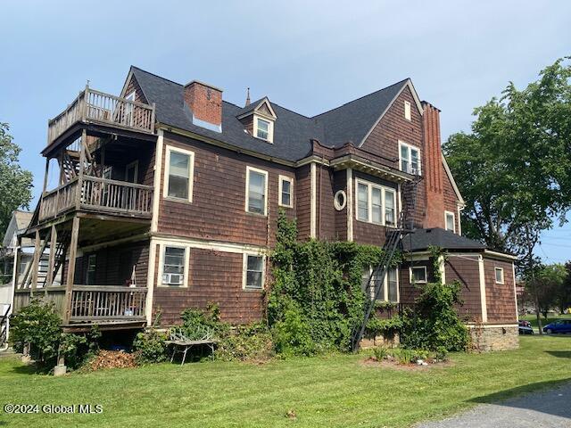 view of property exterior with a balcony, cooling unit, and a lawn