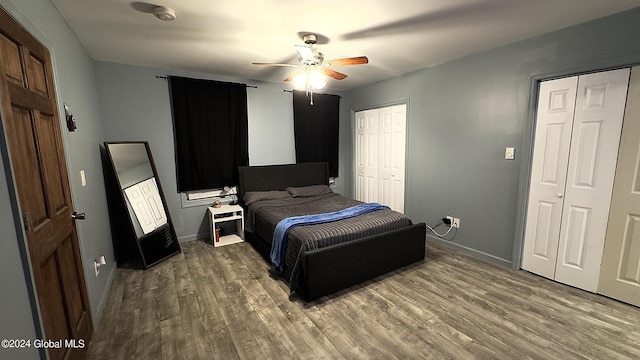 bedroom with hardwood / wood-style flooring, two closets, and ceiling fan