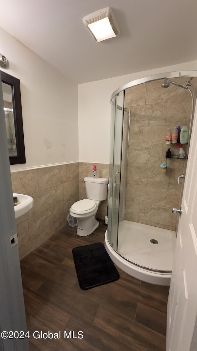 bathroom with tile walls, wood-type flooring, toilet, and walk in shower