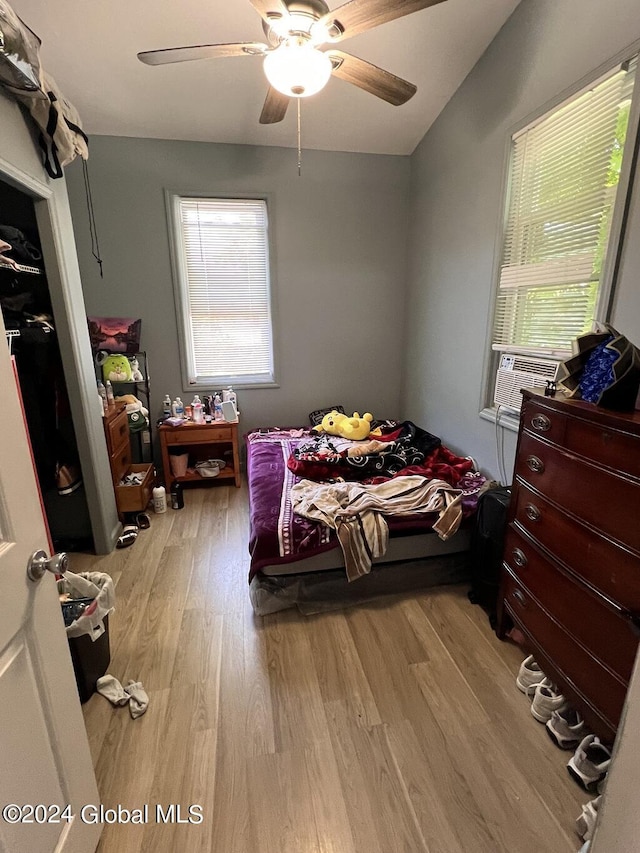 bedroom featuring cooling unit, light hardwood / wood-style flooring, ceiling fan, and vaulted ceiling