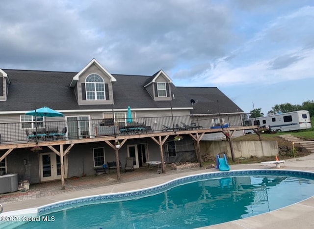 back of property with cooling unit, a pool side deck, and a patio