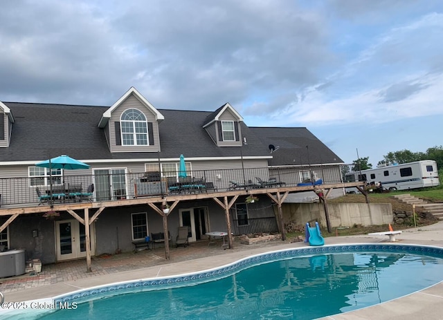 rear view of house with a swimming pool side deck, central AC unit, and a patio area