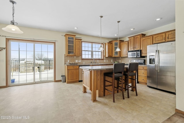 kitchen with sink, hanging light fixtures, stainless steel appliances, a center island, and decorative backsplash