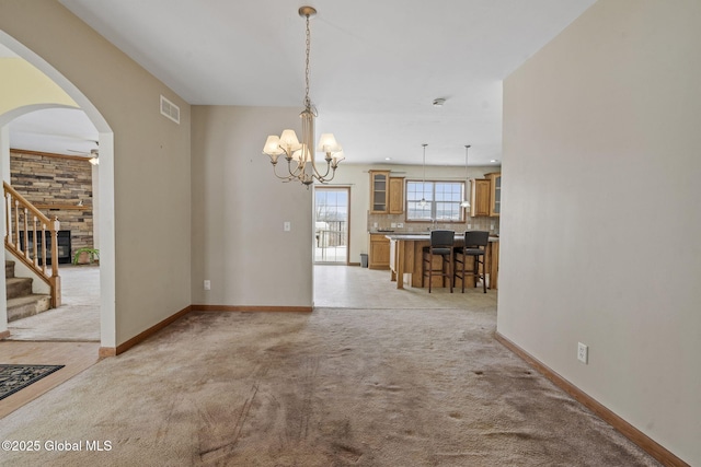 unfurnished dining area with light carpet and ceiling fan with notable chandelier