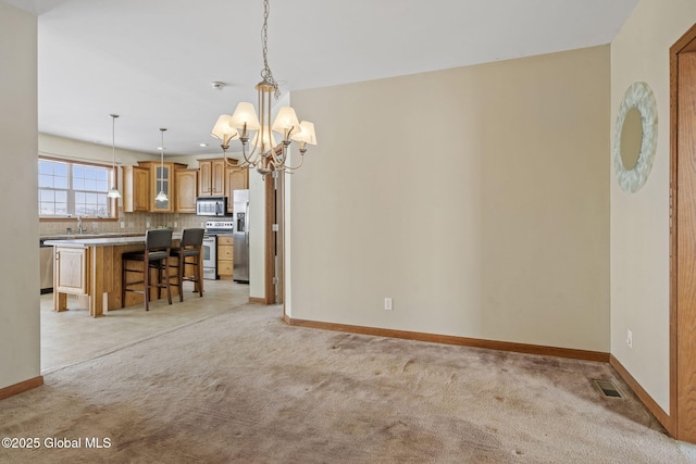 unfurnished dining area featuring sink, light colored carpet, and a notable chandelier