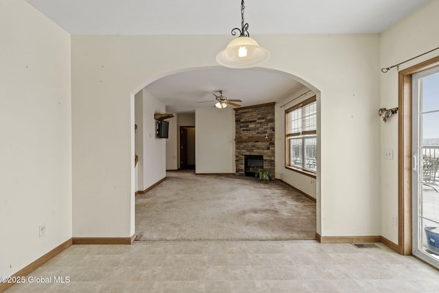 unfurnished living room with ceiling fan, light colored carpet, and a fireplace