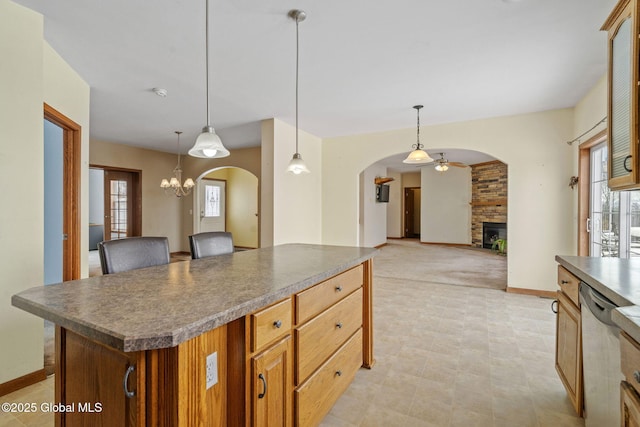 kitchen featuring dishwasher, hanging light fixtures, a fireplace, a healthy amount of sunlight, and a kitchen island