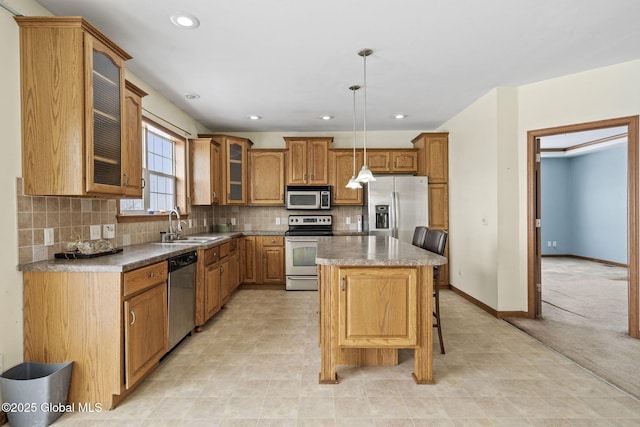 kitchen featuring sink, appliances with stainless steel finishes, a kitchen island, pendant lighting, and decorative backsplash