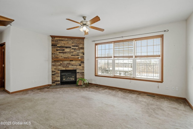 unfurnished living room with ceiling fan, carpet flooring, and a stone fireplace