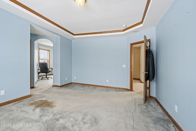 empty room featuring a tray ceiling and light colored carpet