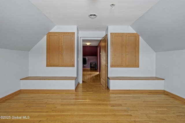 additional living space with vaulted ceiling and light wood-type flooring