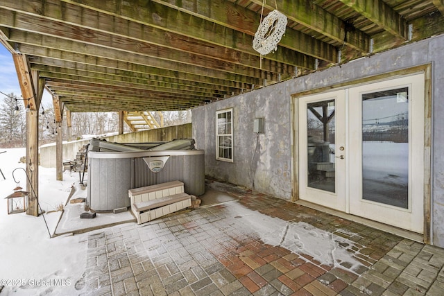 snow covered patio featuring french doors and a hot tub