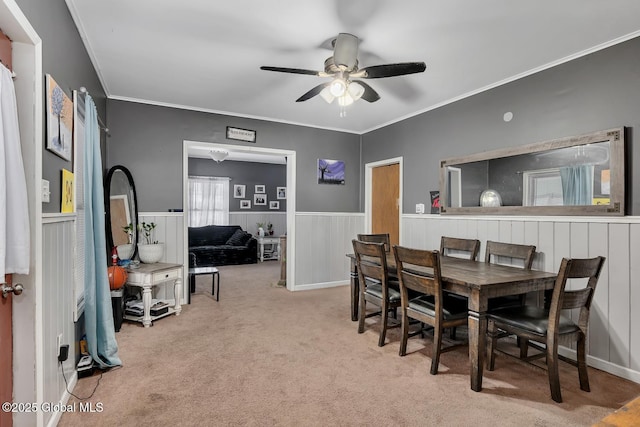 dining space with light colored carpet, ornamental molding, and ceiling fan