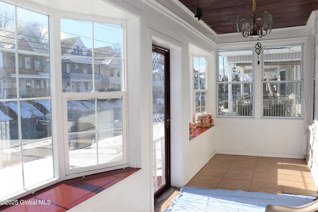 unfurnished sunroom with an inviting chandelier, plenty of natural light, and wooden ceiling