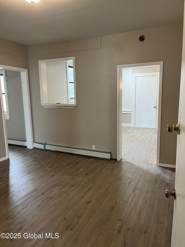 empty room featuring a baseboard heating unit and dark hardwood / wood-style floors