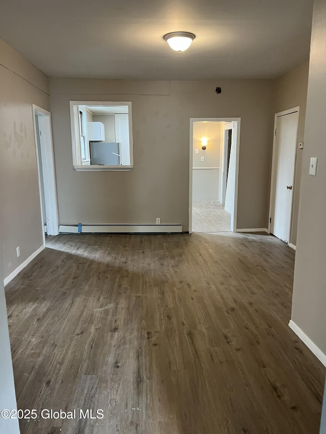 empty room with dark hardwood / wood-style flooring and a baseboard radiator