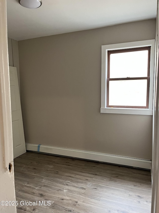 unfurnished room with hardwood / wood-style flooring and a baseboard radiator