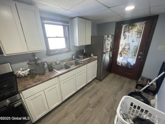 kitchen featuring hardwood / wood-style flooring, white cabinetry, sink, and stainless steel fridge