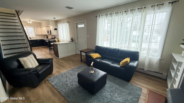 living room with a baseboard heating unit and light hardwood / wood-style flooring