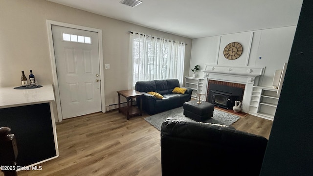 living room featuring a baseboard heating unit and light hardwood / wood-style flooring