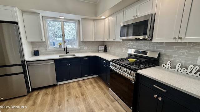 kitchen with white cabinetry, appliances with stainless steel finishes, sink, and light hardwood / wood-style flooring