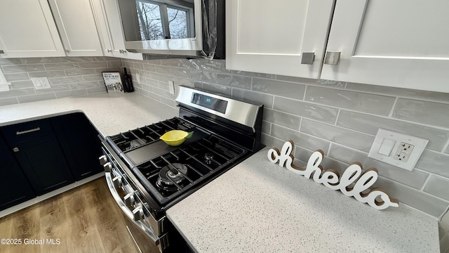 kitchen featuring hardwood / wood-style flooring, white cabinetry, appliances with stainless steel finishes, and decorative backsplash