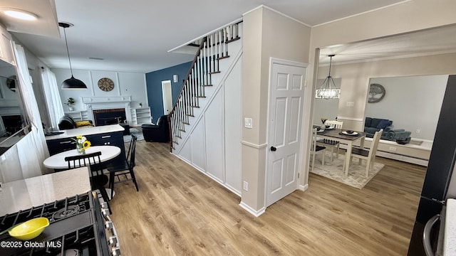 interior space featuring hanging light fixtures, a brick fireplace, a chandelier, and light hardwood / wood-style flooring