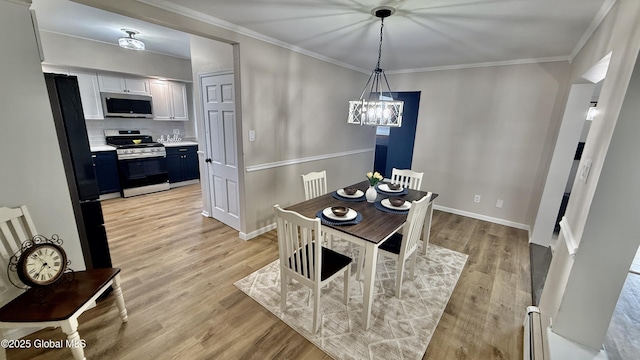 dining room featuring ornamental molding, a baseboard heating unit, a notable chandelier, and light hardwood / wood-style floors