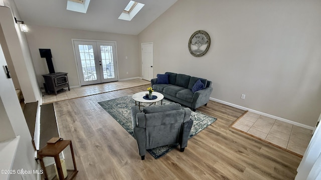 living room with a skylight, light hardwood / wood-style flooring, high vaulted ceiling, and french doors