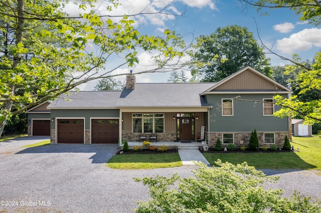 split level home featuring a porch, a front yard, a chimney, stone siding, and an attached garage