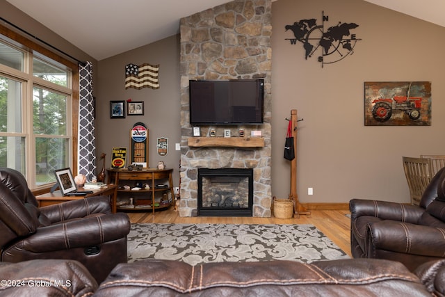 living area with baseboards, wood finished floors, a fireplace, and vaulted ceiling