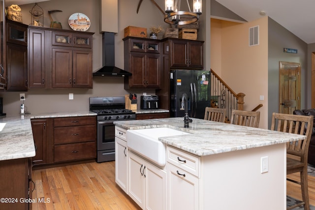 kitchen with visible vents, stainless steel gas stove, a kitchen bar, a sink, and freestanding refrigerator