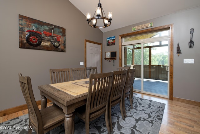 dining room featuring a chandelier, baseboards, light wood-type flooring, and lofted ceiling