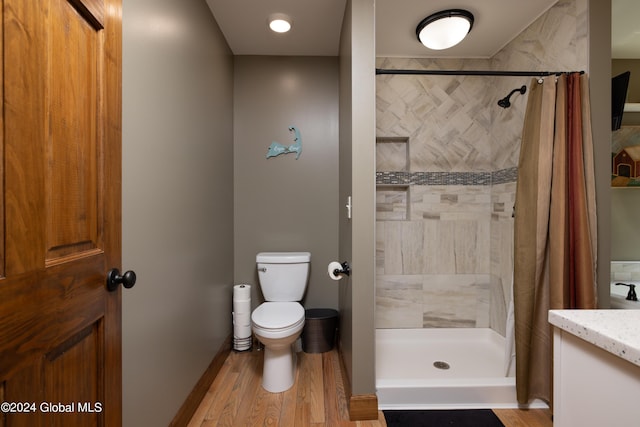 bathroom featuring vanity, toilet, wood finished floors, and a tile shower